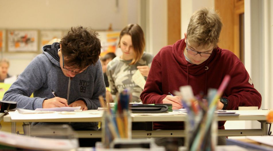 „Leistung macht Schule“ ist eine gemeinsame Initiative von Bund und Ländern. Zwei Jungen sitzen am Schultisch und schreiben.